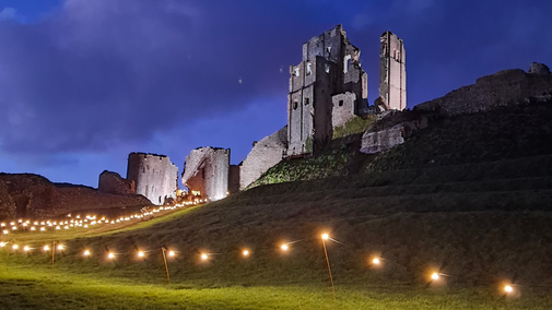 Corfe Castle lit at night with festoon lights around the edge